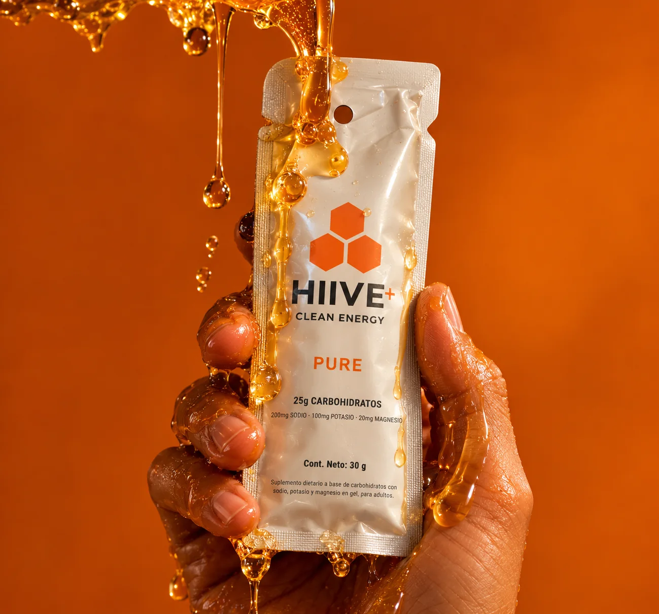 Mano sosteniendo un gel HIIVE PURE bañado en miel, sobre fondo naranja